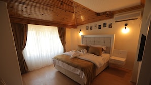 Un dormitorio con techo de madera, una cama con cabecera, una mesita de noche y un aire acondicionado instalado en la pared.