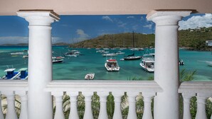 Un puerto deportivo con varias embarcaciones amarradas, rodeado de exuberante vegetación y colinas.