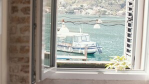 Una habitación con cama, ventana y vistas a un barco y montañas.