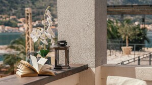 Un balcón con una silla, un libro y una planta pequeña.