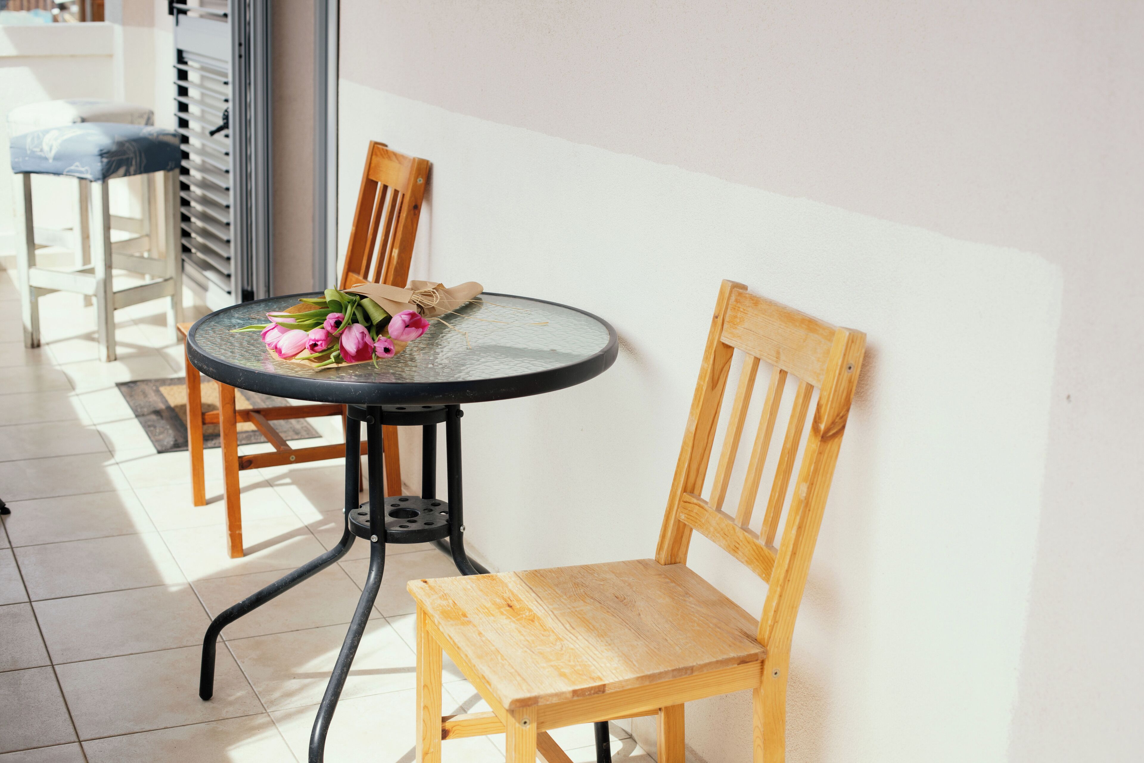 A round table with a glass top, accompanied by a wooden chair with a cushioned seat.