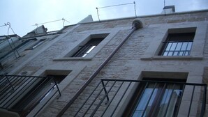 A multi-story building with stone facade, multiple balconies with metal railings, and several windows. - JATTA - Beautiful Stone House Puglia (Conversano)