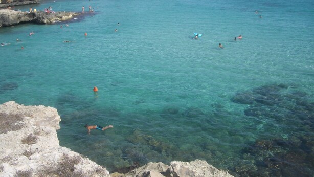 A coastal area with clear turquoise water, rocky formations, and people swimming and sunbathing. - JATTA - Beautiful Stone House Puglia (Conversano)