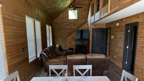 L’intérieur chaleureux d’un chalet comprend une table à manger, des chaises, un canapé et un ventilateur de plafond.