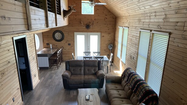 Un intérieur de chalet chaleureux avec une chambre en mezzanine, un coin repas et un salon comprenant un canapé et une table basse.