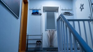 Un pasillo con un zapatero, una puerta, una estrella decorativa y una escalera.