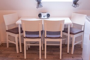 Un petit coin repas avec une table blanche et quatre chaises blanches.