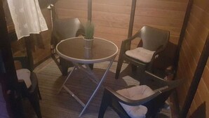Una habitación pequeña y acogedora con una mesa redonda y cuatro sillas, una planta en maceta y suelo de madera.