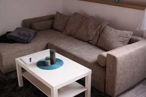 Un salon moderne avec un canapé beige, une table basse blanche et une petite table d’appoint.