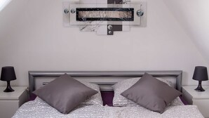 Un dormitorio con una cama, dos mesitas de noche y una obra de arte colgada en la pared.