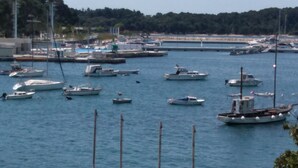 A marina with various boats docked, a bridge in the background, and a forested hill. - Adriatic Sea View Apartment ZOE (Rovinj)