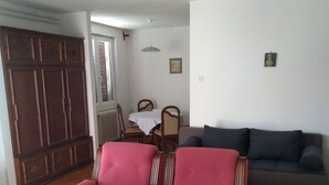 A living room with a wooden wardrobe, a dining table with chairs, a sofa, and a patterned rug. - Adriatic Sea View Apartment ZOE (Rovinj)