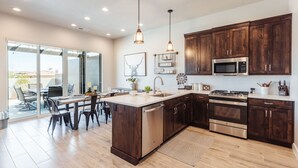 Une cuisine moderne avec des meubles en bois foncé, des appareils électroménagers en acier inoxydable et un grand îlot central.