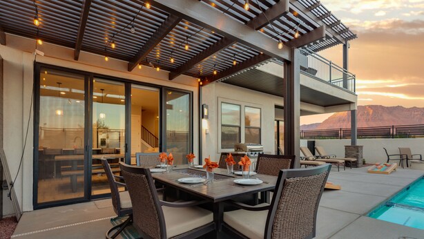 Un espace extérieur aménagé pour les repas, avec une piscine, une terrasse couverte et une vue sur les montagnes.