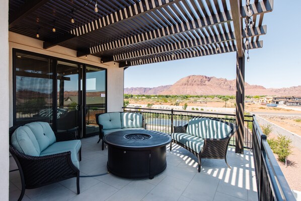 A balcony with wicker furniture, a round table, and a view of a desert landscape. - Ocotillo Springs Resort 70: Private Pool, Hot Tub, and Community Amenities (Santa Clara)