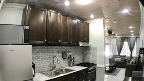 A modern kitchen with dark wood cabinets, a stainless steel refrigerator, and a white tiled backsplash. - Malda House (Dunmore Town)