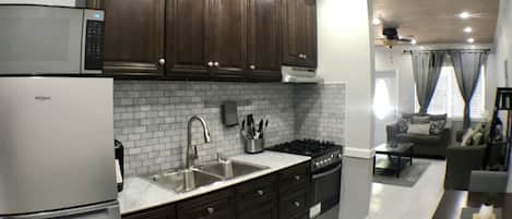 Una cocina moderna con armarios de madera oscura, un refrigerador de acero inoxidable y un salpicadero de azulejos blancos.