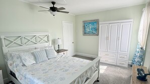 A bedroom with a bed, a ceiling fan, a nightstand, a dresser, and a wardrobe.