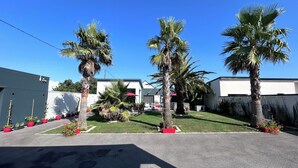 A residential area with palm trees, a white building, and a garage. - New house, Jacuzzi, Terrace, Near to Beaches and Shops (Le Tour-du-Parc)
