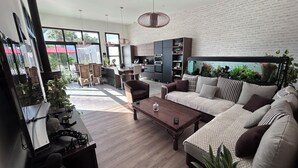 A modern living room with a sofa, coffee table, and dining area. - New house, Jacuzzi, Terrace, Near to Beaches and Shops (Le Tour-du-Parc)