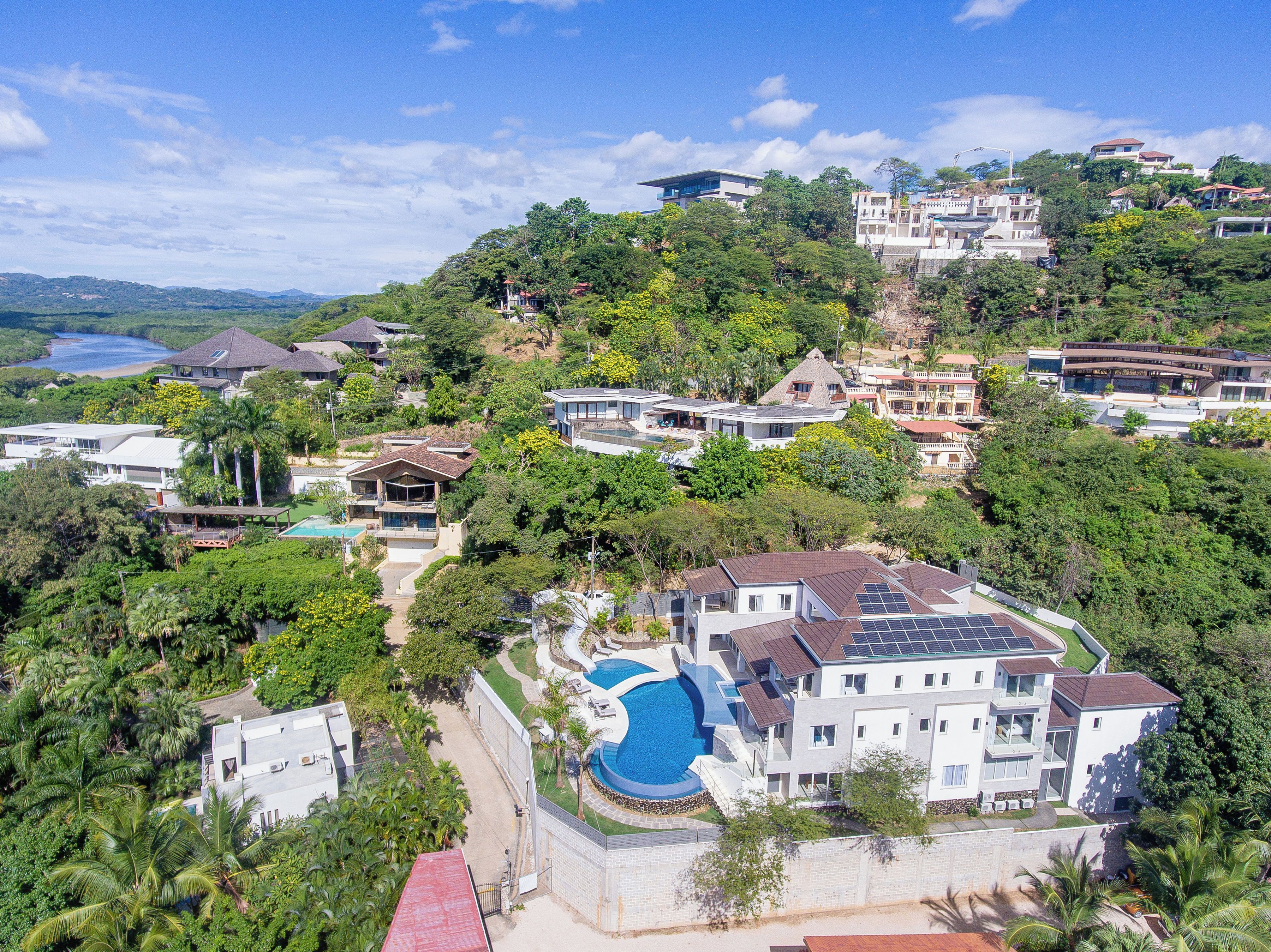 A residential area with multiple houses, a swimming pool, and a view of a body of water.