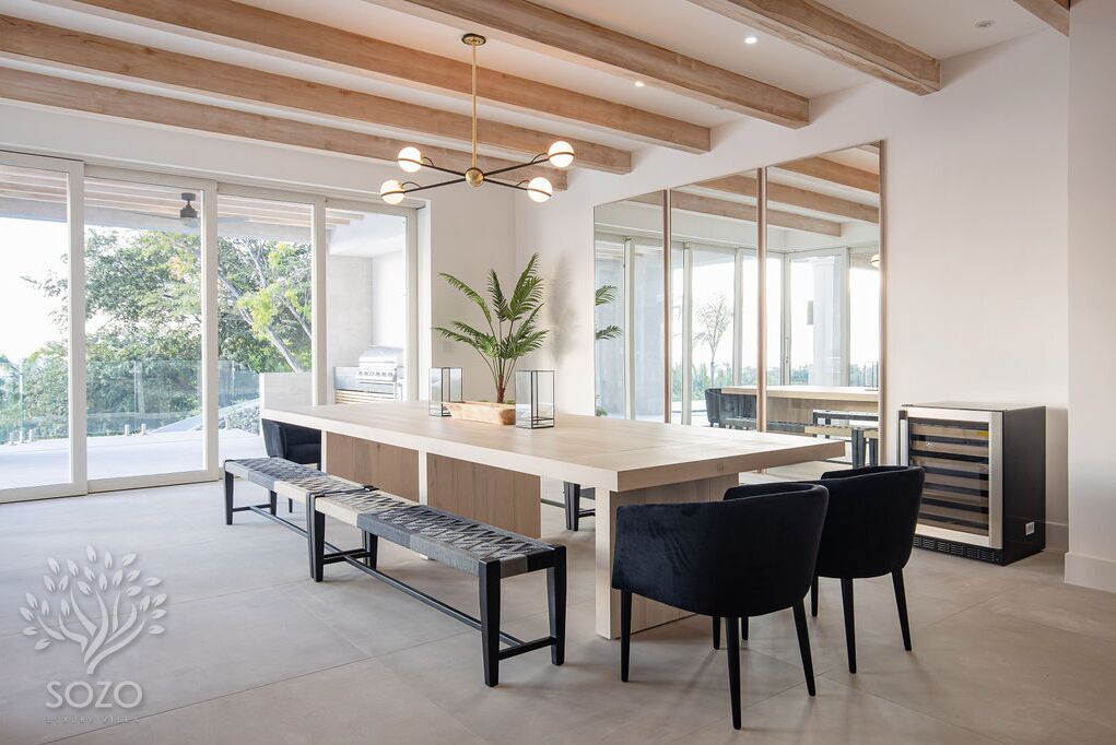 Una cocina moderna con una isla grande, sillas negras y una planta en maceta.