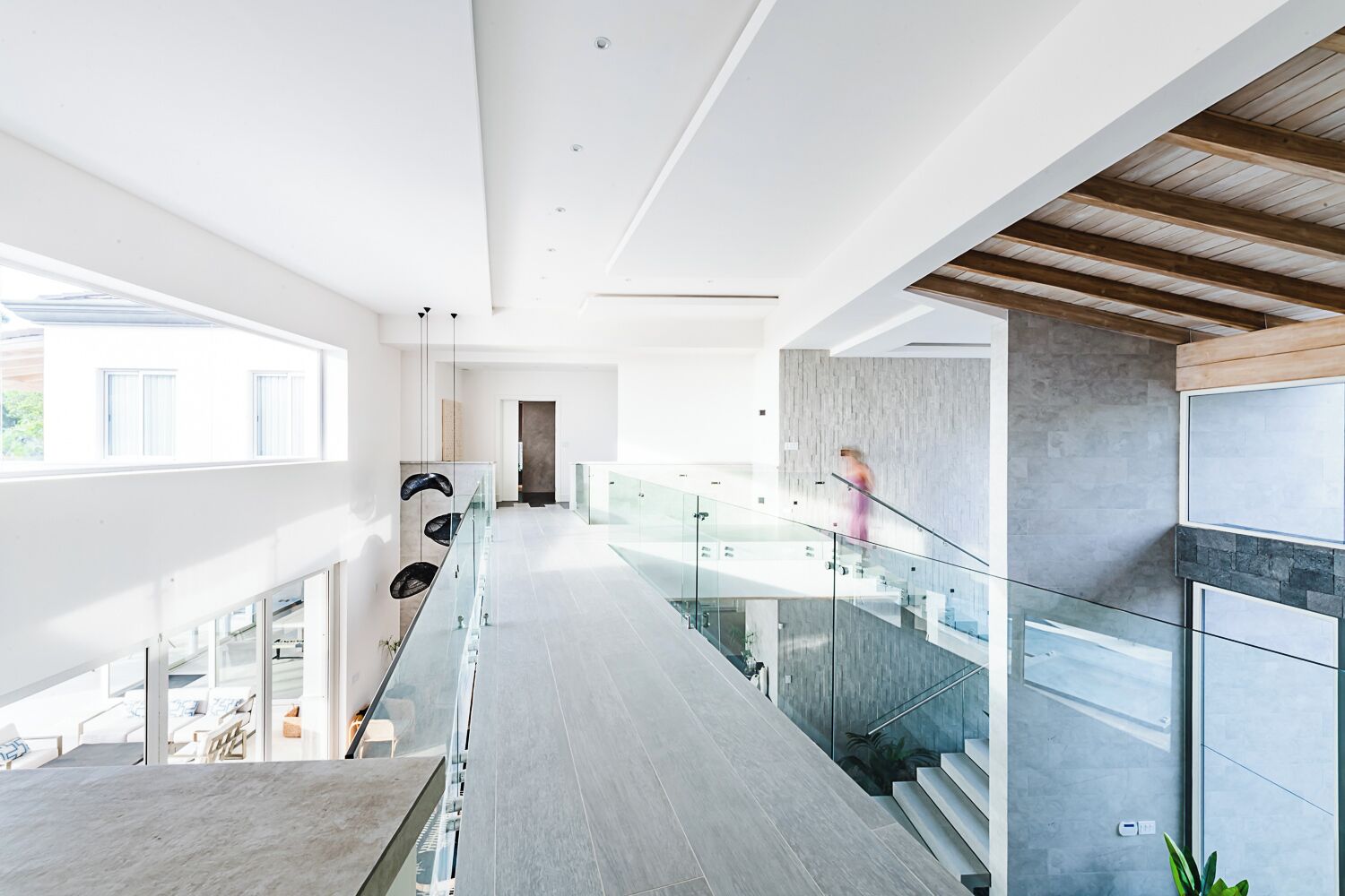 A modern interior with a glass staircase, a wooden ceiling, and a view of the outdoors.