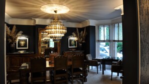 Ein formeller Speisesaal mit einer Chandelier, Holzwänden und Blick ins Freie.