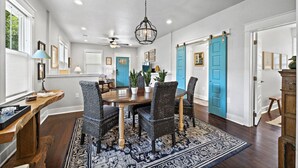 A dining area with a wooden table, wicker chairs, and a patterned rug.
