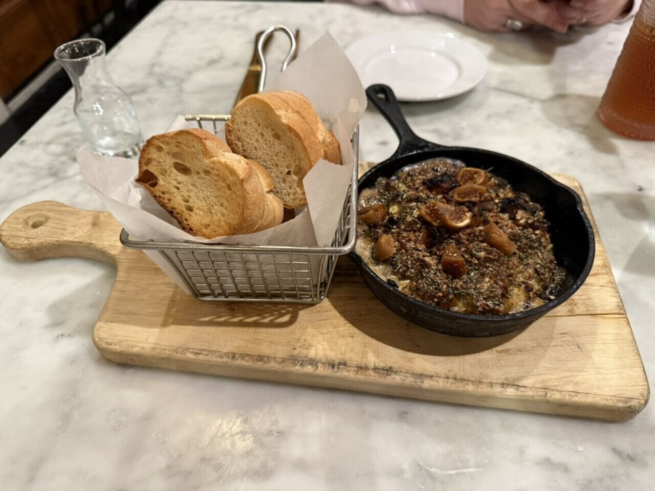 Un plat a la planxa amb pa sobre un tauler de fusta.