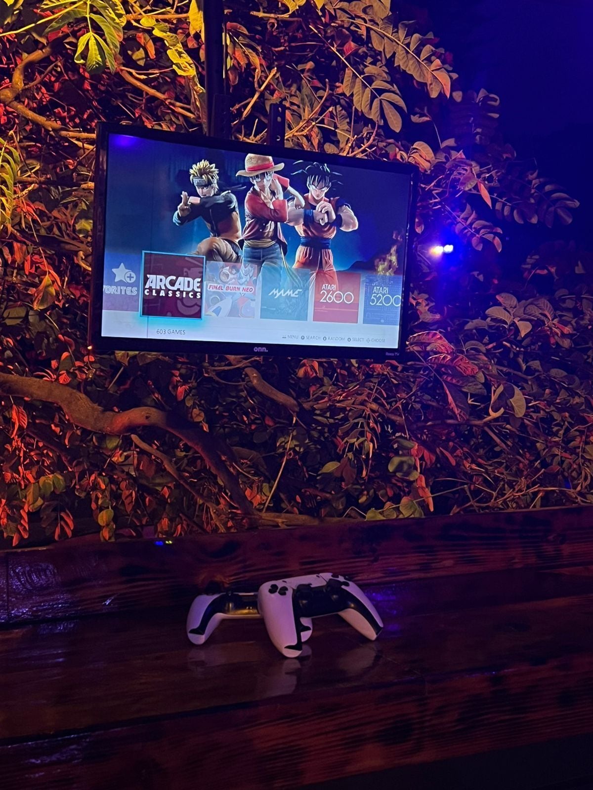 A television displaying video game titles, a game controller, and a wooden surface.