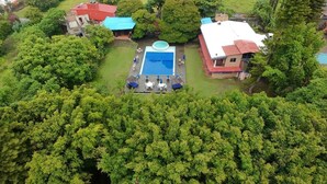 An aerial view of a property with a swimming pool, surrounded by lush greenery and multiple buildings. - Hospedaje Los Cruxes Tepoztlan (Tepoztlán)