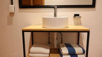 A bathroom with a white sink, a mirror, a towel rack, and a towel dispenser.