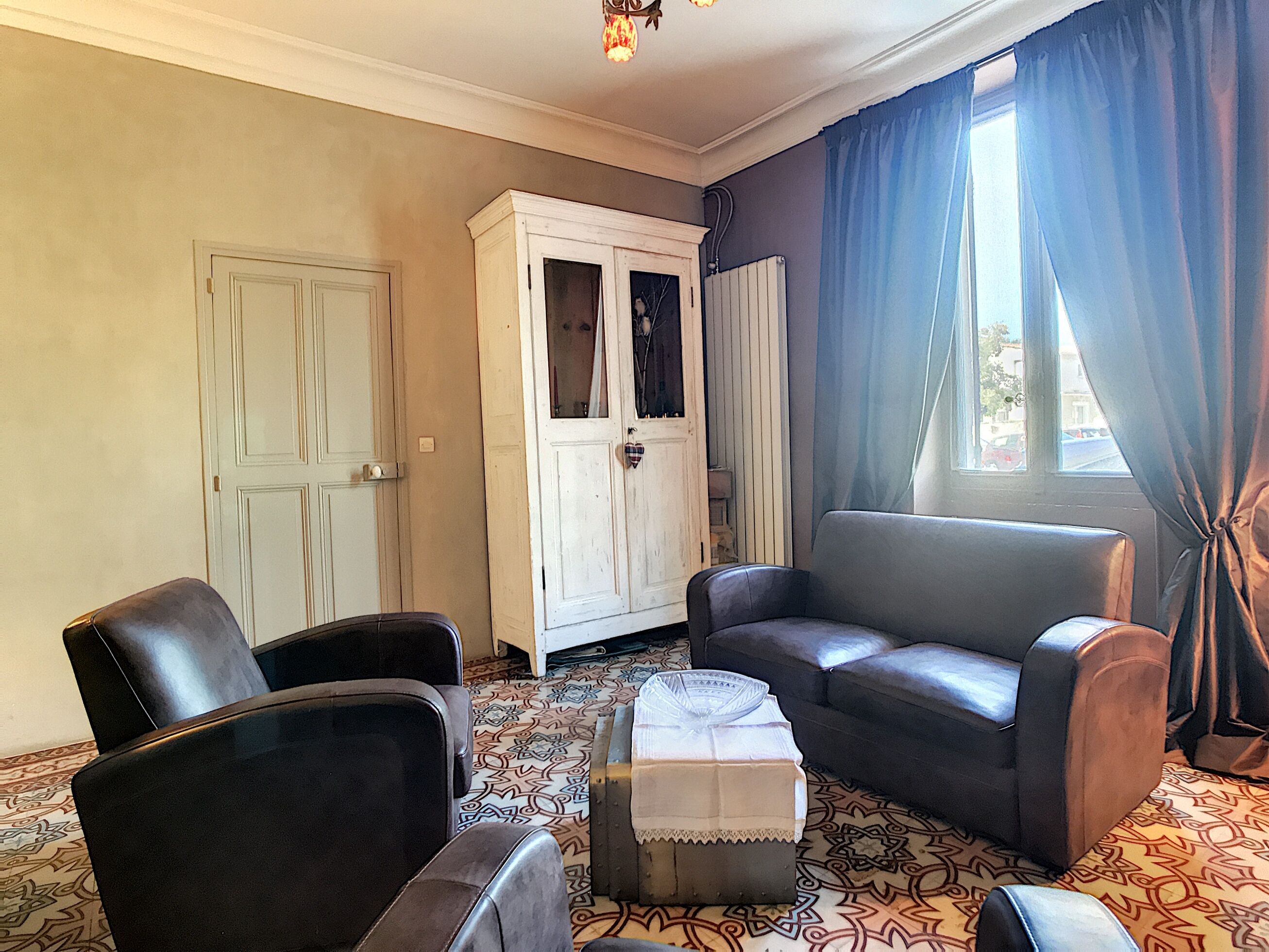 A living room with two leather armchairs, a white cabinet, and a patterned carpet.