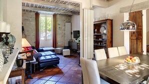 A spacious living area with a dining table, chairs, a sofa, and a television. - Le 115, air-conditioned town house with interior courtyard and swimming pool (Pernes-les-Fontaines)