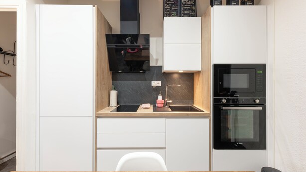 Una cocina compacta con microondas, horno y una pequeña encimera.