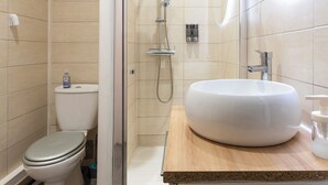 Un baño moderno con ducha envuelta en vidrio, lavamanos blanco y un inodoro.