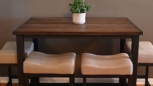 Een houten eettafel met twee gewatteerde banken en een potplant erop.