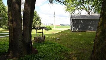 A rural property with a stone well, a wooden shed, and a fenced area.
