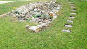 Een tuin met een kleine waterval, rotsen en diverse planten.