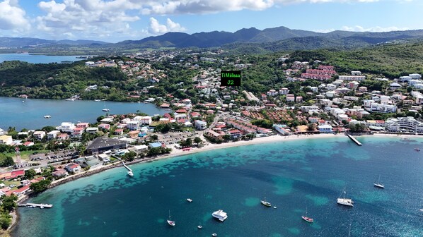A coastal town with buildings, a beach, and boats. - Ti Mélissa - Swimming Pool, Ocean View, Parking (Trois-Ilets)