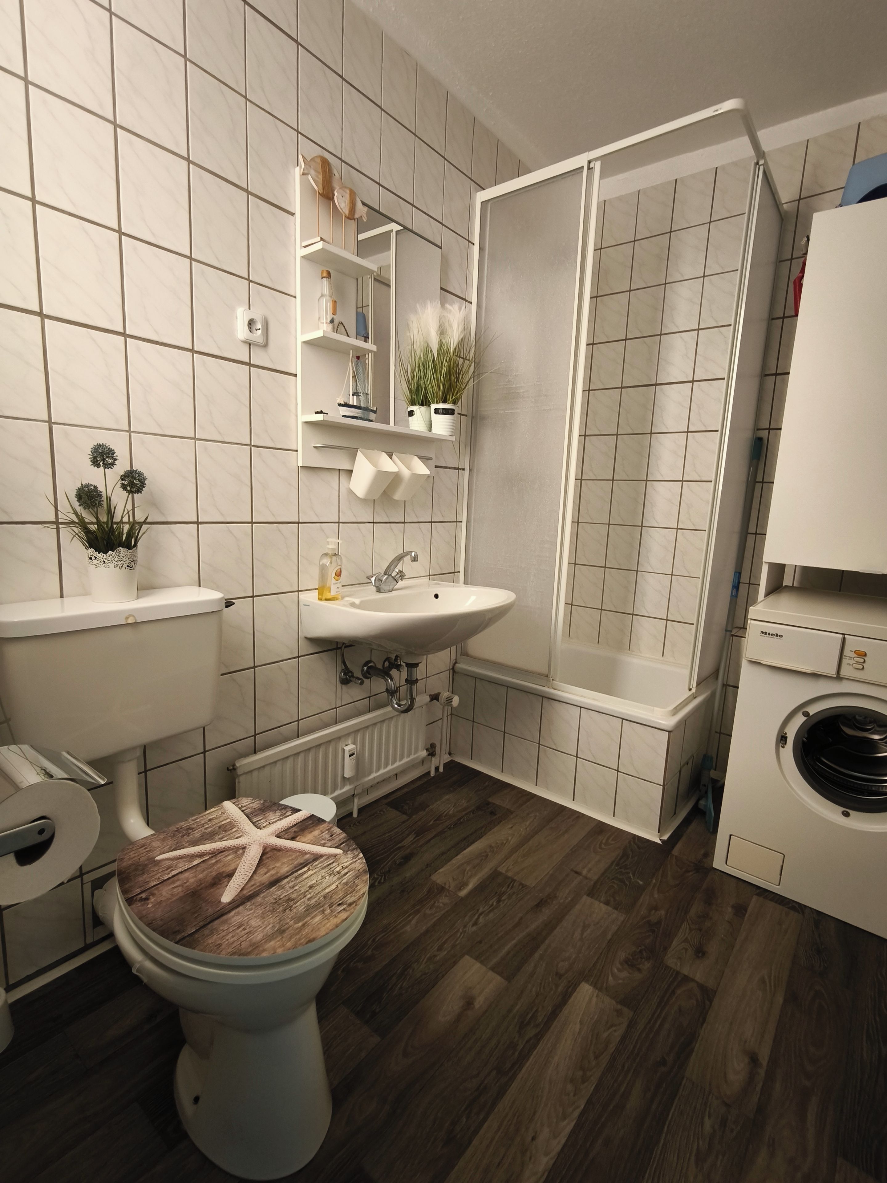 Baño con inodoro, lavamanos, ducha y lavadora.
