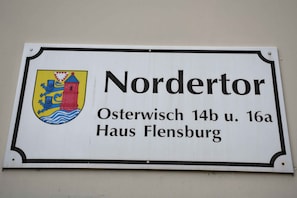 Una señal con el nombre 'Nordertor' y la dirección 'Osterwisch 14b u. 16a Haus Flensburg'.