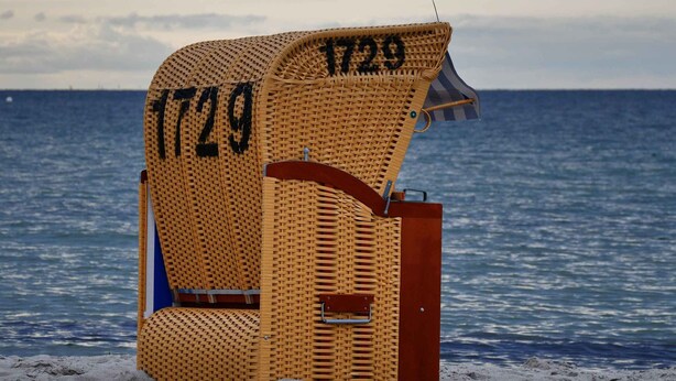 A beach chair with the number 1729 on it, located on a sandy beach with the ocean in the background.