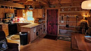 A cozy cabin-style kitchen with wooden cabinets, a stove, and a red door. - Beautiful Sunsets & Amazing Stars in every season, Family-owned gem (Meadows of Dan)