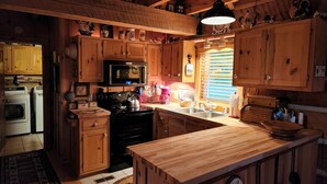 A rustic kitchen with wooden cabinets, a microwave, stove, and a large island. - Beautiful Sunsets & Amazing Stars in every season, Family-owned gem (Meadows of Dan)
