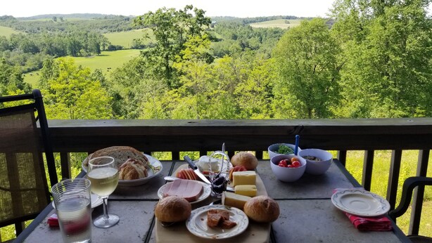A table set with food and drinks on a balcony with a scenic view. - Beautiful Sunsets & Amazing Stars in every season, Family-owned gem (Meadows of Dan)