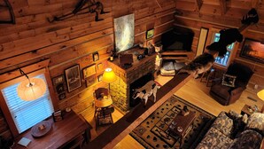 A cozy log cabin interior with a fireplace, wooden walls, a stone fireplace, a sofa, and a television. - Beautiful Sunsets & Amazing Stars in every season, Family-owned gem (Meadows of Dan)