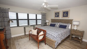 A bedroom with a bed, a wooden bench, a ceiling fan, and a nightstand with lamps.