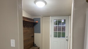 Ein Flur mit einer Holzbank, einer Tür und einem an der Wand befestigten Regal.